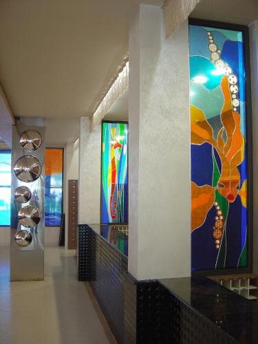 A vibrant modern art gallery hallway features colorful abstract murals and sleek metallic sculptures, creating an inviting atmosphere for cultural exploration and artistic inspiration.