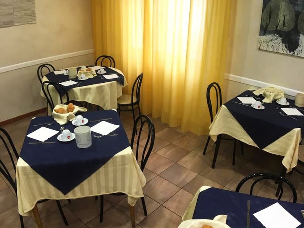 A cozy café interior with neatly set tables draped in navy blue and beige cloths, framed by warm yellow curtains, creates an inviting atmosphere perfect for travelers seeking a quiet breakfast spot.