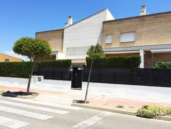 A serene suburban street features modern houses with manicured hedges and trees, ideal for families seeking a peaceful residential area with easy access to amenities.