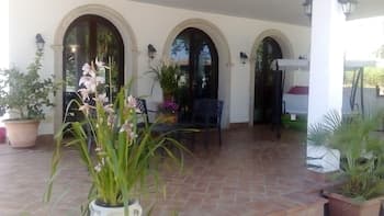 A serene patio with arched doorways, potted plants, and tiled flooring evokes a tranquil Mediterranean vibe, perfect for travelers seeking relaxation in a cozy outdoor setting.