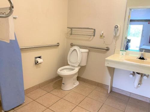 A clean, accessible bathroom with tiled floors, grab bars, and a sink offers a functional space ideal for travelers needing mobility assistance.