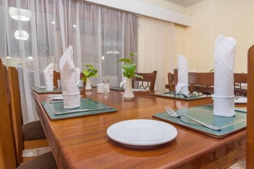 A cozy indoor dining area with neatly set wooden tables, white napkins, and green placemats, perfect for travelers seeking a comfortable and inviting restaurant experience.