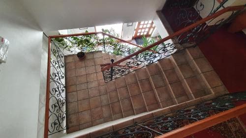 A cozy indoor staircase with ornate wrought-iron railings overlooks a tiled atrium adorned with greenery, ideal for travelers seeking charming accommodations in a historic setting.