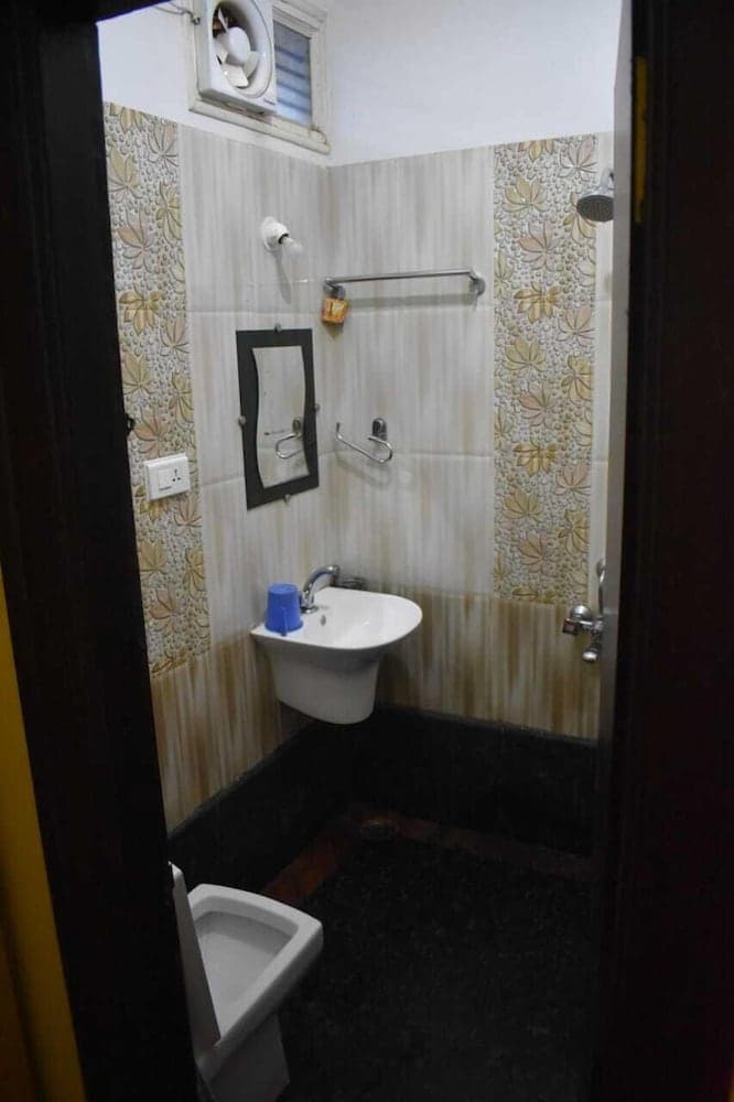 A cozy bathroom with floral wallpaper, a sink, mirror, and shower setup offers a practical space for travelers seeking comfort in compact accommodations.