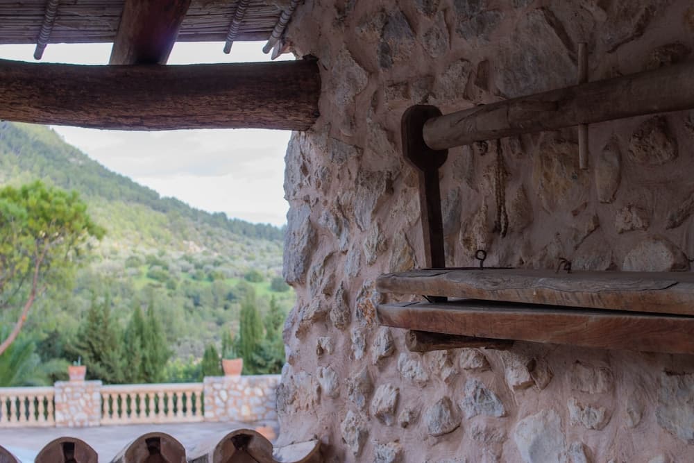 A rustic stone wall with wooden beams frames a serene view of lush green hills, ideal for travelers seeking tranquil countryside retreats.
