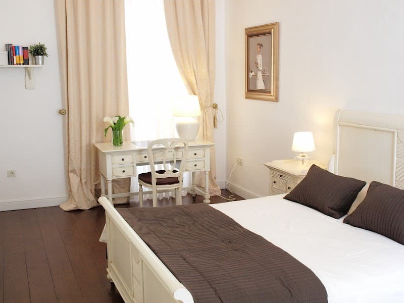 A cozy bedroom in Dubrovnik features elegant white furniture, soft lighting, and a serene ambiance, ideal for travelers seeking a charming and comfortable stay.