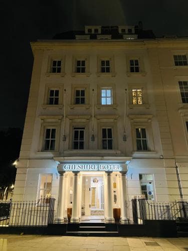 A charming, well-lit hotel facade with classical architecture stands invitingly at night, perfect for travelers seeking a cozy urban retreat in a bustling city center.