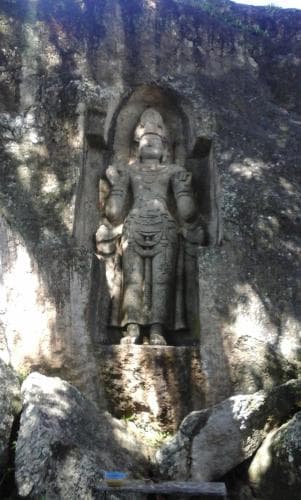 A majestic ancient stone statue carved into a rocky cliffside evokes a sense of historical reverence, ideal for cultural heritage tourism and spiritual exploration.