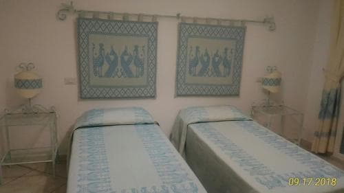 A cozy hotel room features twin beds adorned with blue peacock-patterned linens, matching wall hangings, and elegant bedside lamps, creating a serene atmosphere ideal for travelers seeking comfort and tranquility.