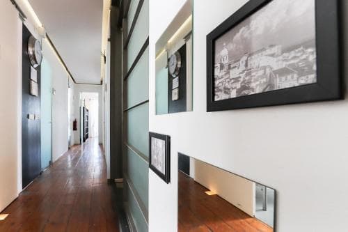 A cozy hotel hallway adorned with framed black-and-white cityscape photos and vintage clocks creates an inviting atmosphere, perfect for travelers seeking a charming and artistic accommodation experience.