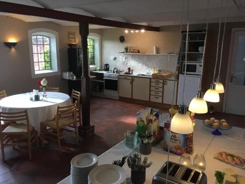 A cozy, rustic kitchen with warm lighting, wooden beams, and tiled floors creates an inviting atmosphere perfect for a family gathering or a relaxing retreat, featuring modern appliances and a dining area set for breakfast.