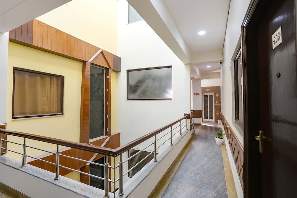 A serene hotel corridor features polished floors, wooden accents, framed artwork, and a staircase, ideal for travelers seeking a comfortable stay in a modern setting.