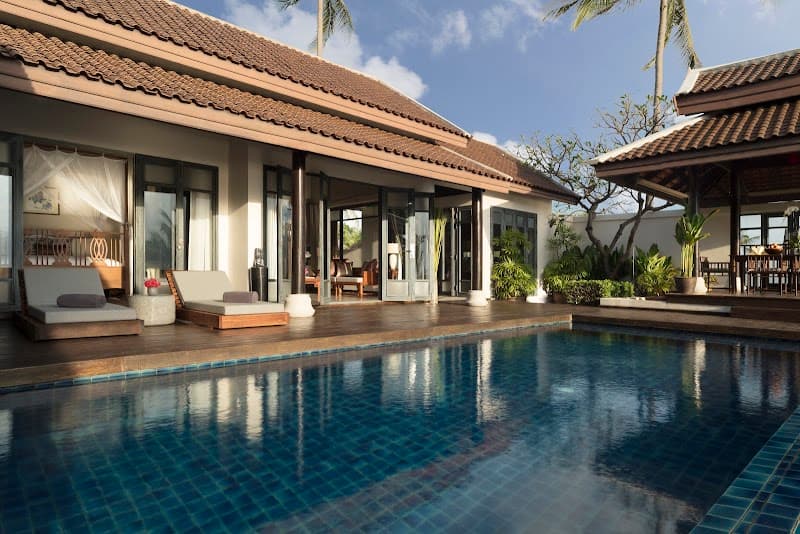 A serene tropical villa with a private pool, lush greenery, and cozy loungers invites travelers to unwind in luxury at a resort in Koh Samui, Thailand.