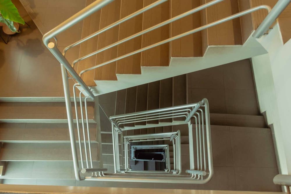 A modern spiral staircase with sleek metal railings and wooden steps creates an inviting and stylish atmosphere in an urban loft, perfect for travelers seeking contemporary design elements in their accommodations.