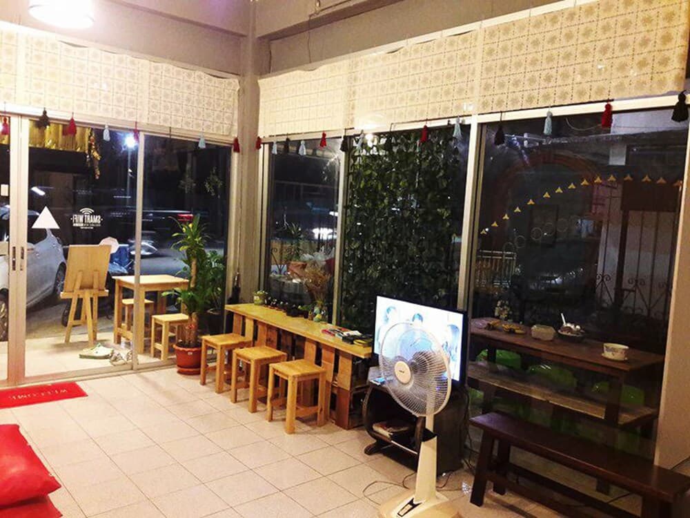 A cozy indoor café with wooden furniture, festive decorations, and a fan creates a relaxed atmosphere ideal for travelers seeking a quiet spot to unwind and enjoy refreshments.