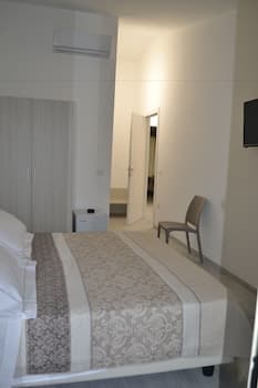 A cozy hotel room features a neatly made bed with patterned bedding, a modern chair, and soft lighting, creating a serene atmosphere ideal for travelers seeking relaxation.