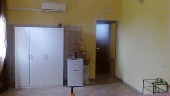 A cozy, minimally furnished room with yellow walls, white wardrobes, and tiled flooring exudes a calm atmosphere, ideal for travelers seeking a simple and functional accommodation space.