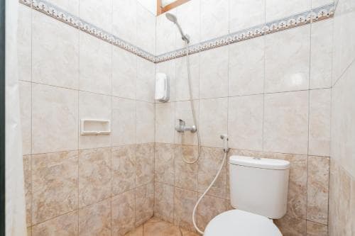 A clean, tiled bathroom with a showerhead, toilet, and soap holder offers a practical space for travelers seeking basic amenities in a compact setting.