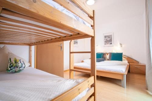 A cozy hostel room featuring wooden bunk beds and single beds adorned with colorful pillows, creating a welcoming atmosphere ideal for budget travelers seeking comfortable accommodations.