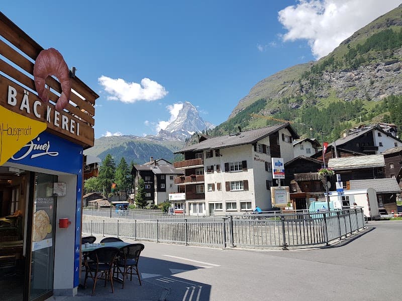 A charming bakery in a quaint Swiss village offers a picturesque view of the majestic Matterhorn, perfect for travelers seeking a serene alpine retreat.