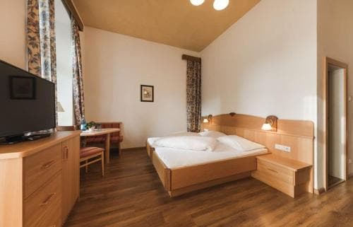 A cozy hotel room with wooden furnishings, warm lighting, and a neatly made bed offers a comfortable retreat for travelers seeking relaxation.