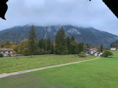 A serene rural landscape featuring lush green fields, scattered houses, and towering mist-covered mountains, ideal for tranquil countryside retreats and nature photography.