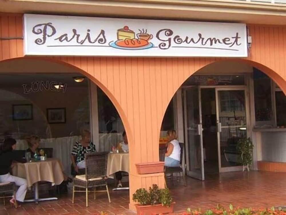 A cozy café with arched entryways and a "Paris Gourmet" sign invites travelers to enjoy its inviting ambiance, perfect for a leisurely lunch or coffee break.