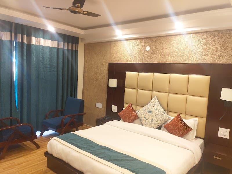 A cozy hotel room in Leh features a plush bed with decorative pillows, wooden flooring, and blue curtains, ideal for travelers seeking comfort in the Himalayan region.