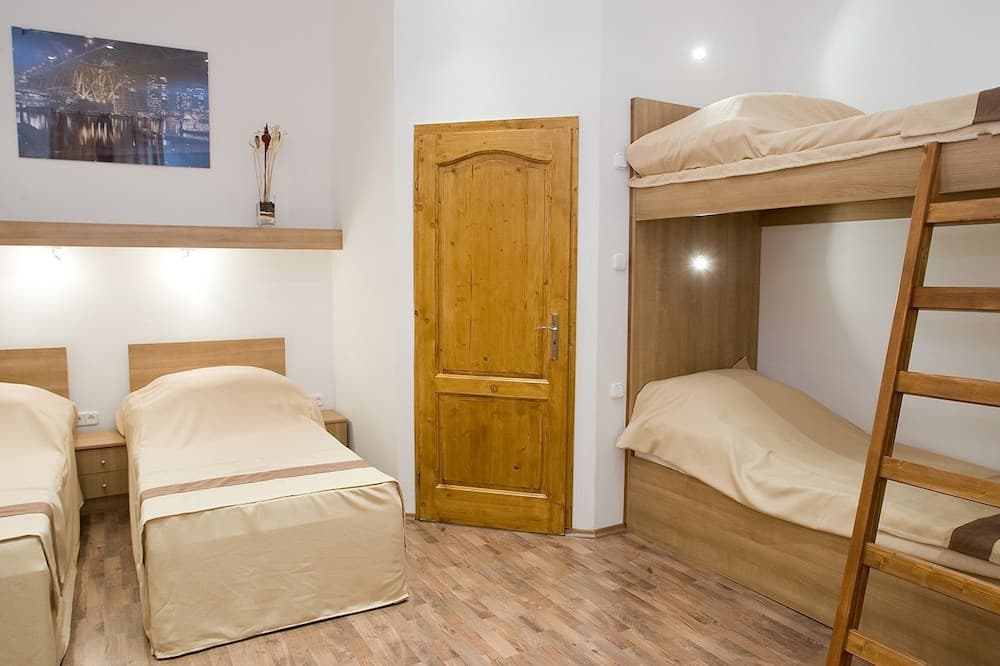 A cozy hostel room with wooden bunk beds, single beds, and warm lighting creates an inviting atmosphere ideal for budget travelers seeking comfort.