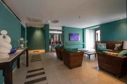 A cozy hotel lobby with teal walls, wicker furniture, and a striped rug creates a welcoming atmosphere, ideal for travelers seeking relaxation and comfort during their stay.