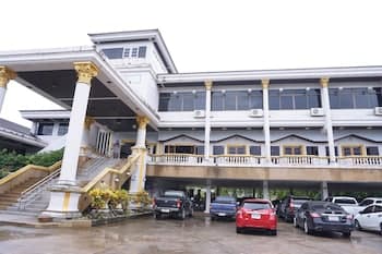 A grand two-story building with ornate golden columns and a covered parking area below exudes elegance in an urban setting, ideal for travelers seeking luxurious accommodations or event venues.