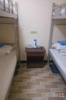 A cozy dormitory-style room with bunk beds, tiled flooring, and a small table featuring a water dispenser, ideal for budget travelers seeking simple accommodations.