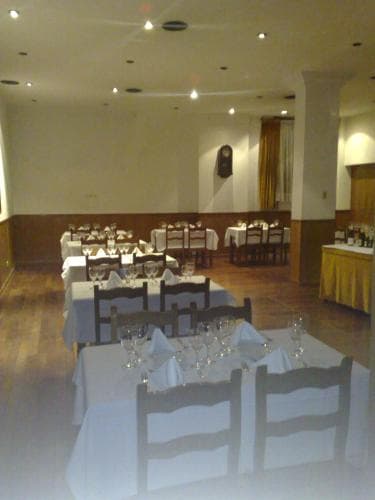 A warmly lit banquet hall with neatly arranged tables, chairs, and glassware creates an inviting atmosphere ideal for group dining or event planning.