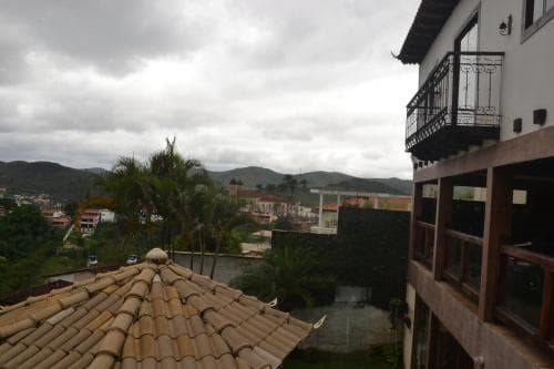 A serene balcony view overlooking tiled rooftops and lush greenery under a cloudy sky, ideal for travelers seeking a tranquil retreat in a hillside town.