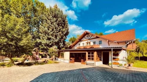 A charming countryside villa with a red-tiled roof and lush greenery offers a serene retreat, perfect for travelers seeking relaxation in a picturesque rural setting.