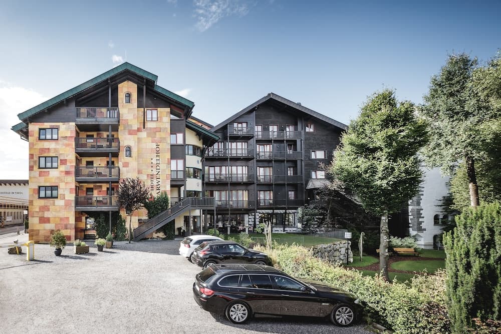 A charming alpine hotel complex with colorful facades and lush greenery offers a serene retreat for travelers seeking relaxation and scenic views.