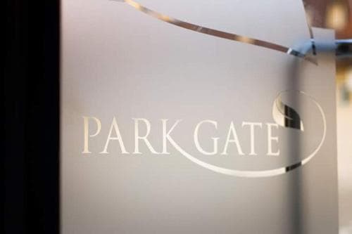 A sleek glass door featuring the elegant "Park Gate" logo invites travelers to explore a modern urban retreat, ideal for business or leisure stays.