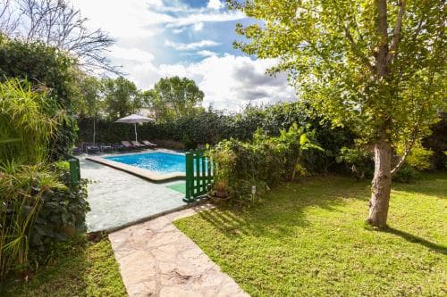 A serene garden oasis features a tranquil pool surrounded by lush greenery, ideal for relaxing vacations and family getaways.