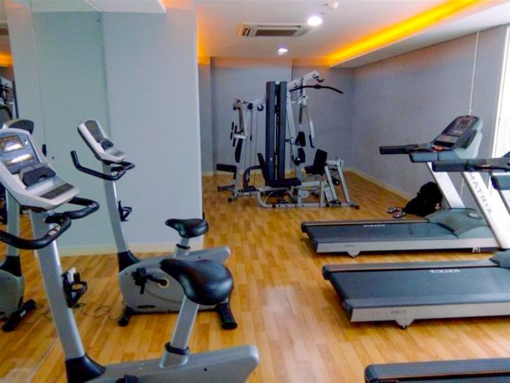 A well-equipped indoor gym featuring treadmills, stationary bikes, and weight machines on wooden flooring, ideal for travelers seeking fitness amenities during their stay.