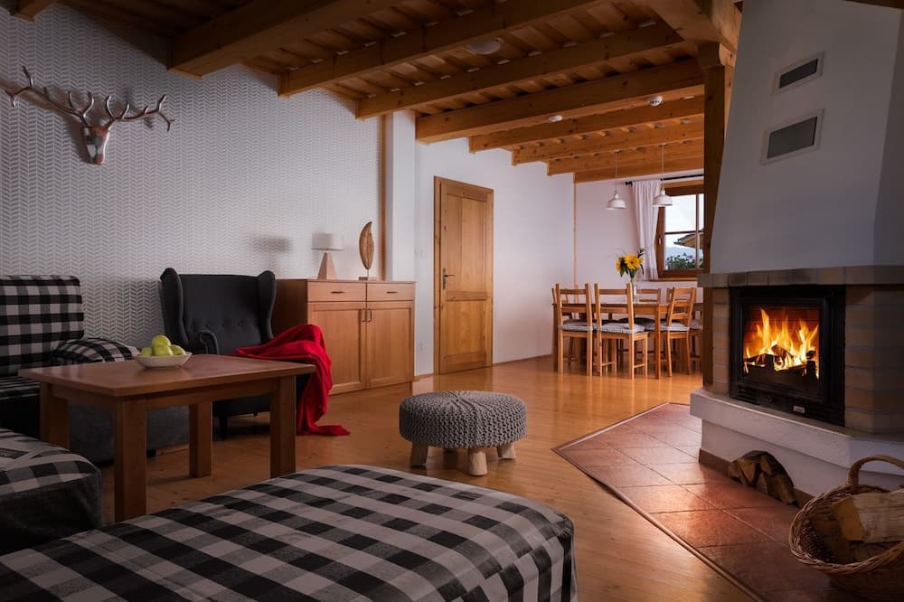 A cozy cabin interior with a warm fireplace, wooden beams, checkered furniture, and rustic decor invites travelers seeking a serene retreat in a mountain lodge setting.