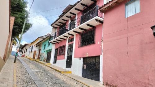 A charming cobblestone street lined with colorful colonial-style buildings featuring balconies and vibrant facades creates a picturesque setting ideal for cultural exploration and photography.