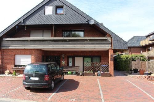 A cozy residential house with a brick facade and black roof stands invitingly on a sunny day, featuring a parked car in the driveway, ideal for travelers seeking a quiet suburban getaway.