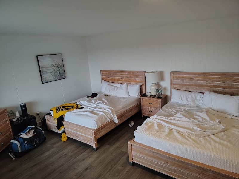 A cozy hotel room with two wooden beds, a rustic ambiance, and personal belongings scattered around, ideal for travelers seeking comfort at the Castle Manor Inn in Gloucester, MA.