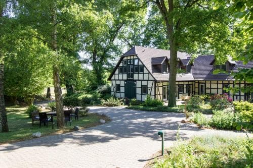 A serene countryside retreat features a charming half-timbered house surrounded by lush greenery, ideal for a peaceful getaway or family vacation.