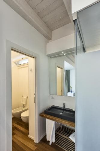 A cozy modern bathroom with wooden flooring, a sleek sink vanity, and a glass-enclosed shower exudes a serene and stylish ambiance, ideal for travelers seeking comfort in boutique accommodations.