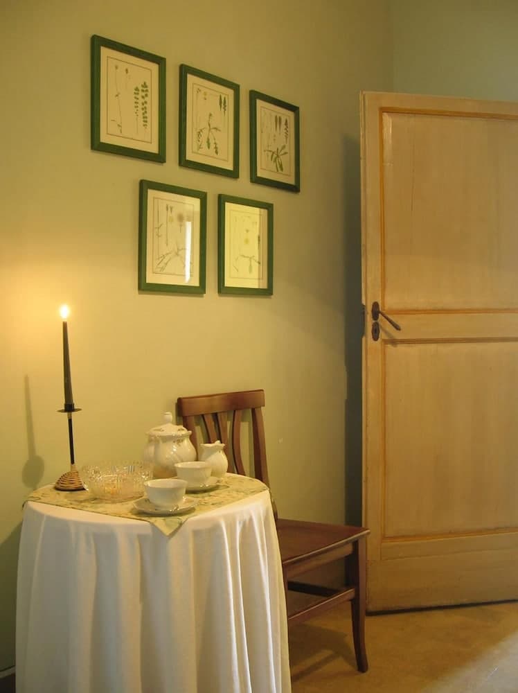 A cozy corner with a softly lit table set for tea under botanical prints, evoking a serene atmosphere ideal for a tranquil getaway or a quiet retreat experience.
