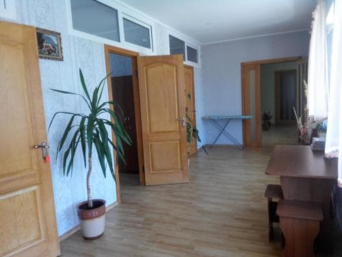 A cozy apartment hallway with wooden doors, a potted plant, and a small table creates a welcoming atmosphere, ideal for travelers seeking a homely stay.