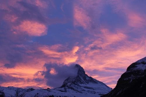 A breathtaking mountain landscape under a vibrant pink and purple sunset sky, ideal for adventure seekers exploring alpine regions.