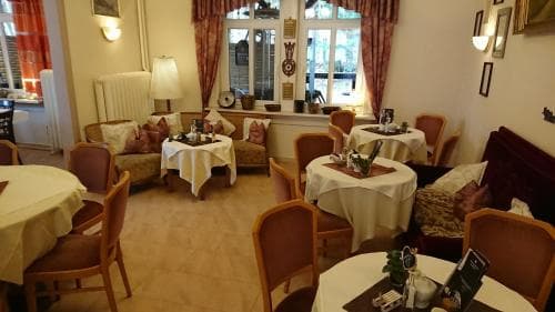 A cozy café interior with warm lighting, wooden furniture, and round tables set for dining creates an inviting atmosphere perfect for travelers seeking a relaxing spot to enjoy a meal or coffee.