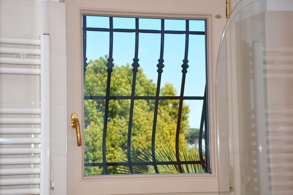 A serene bathroom scene features a window with elegant black bars framing lush greenery outside, ideal for travelers seeking a tranquil retreat with natural views.